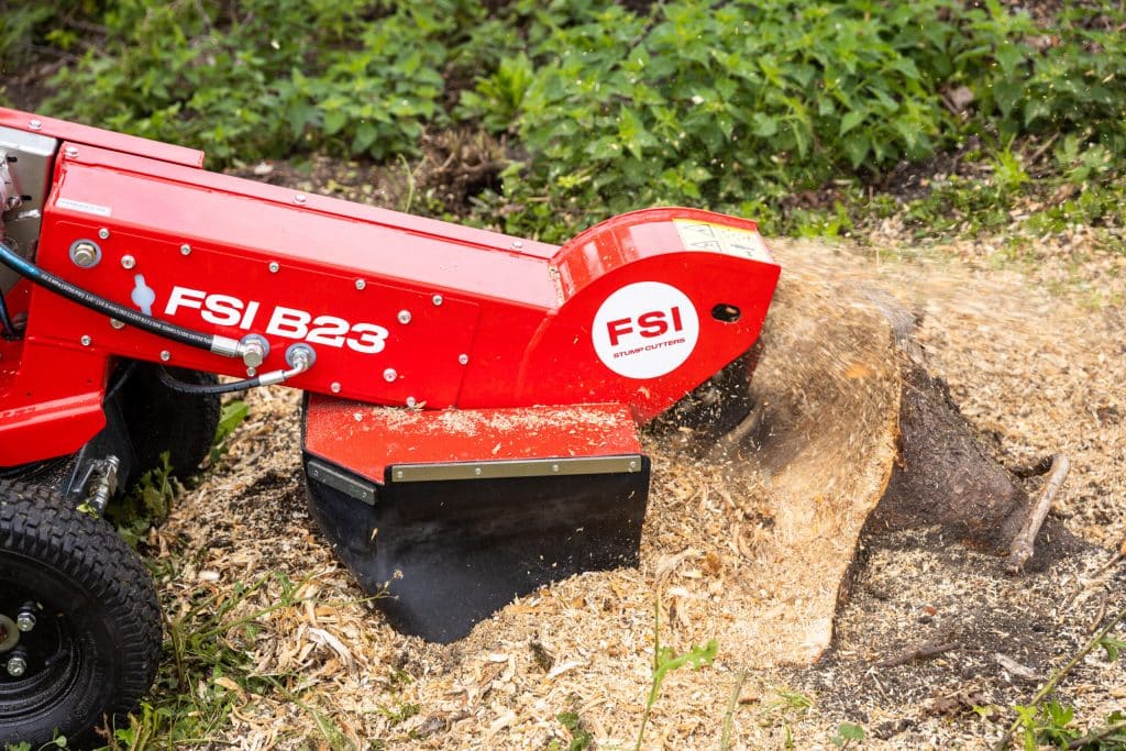 FSI B23 stump grinder cutting wheel removing a stump with wood chips flying