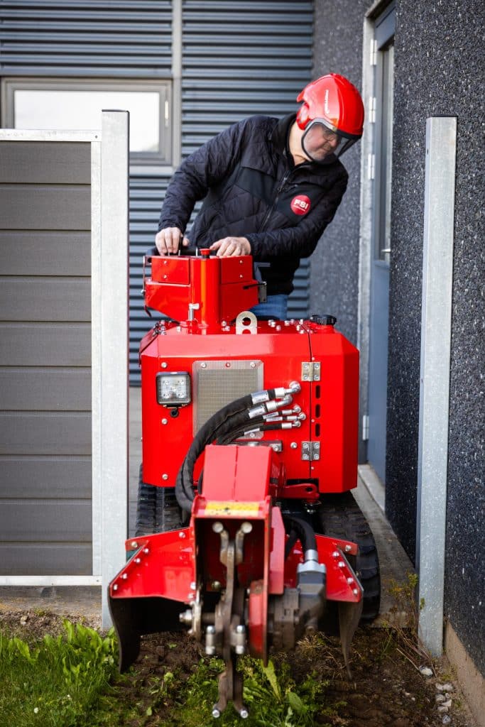 Operator using FSI B31-980 stump grinder in a narrow gap between buildings